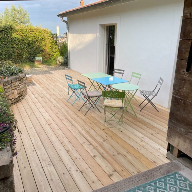 Terrasse en bois clair avec table et chaises de jardin colorées